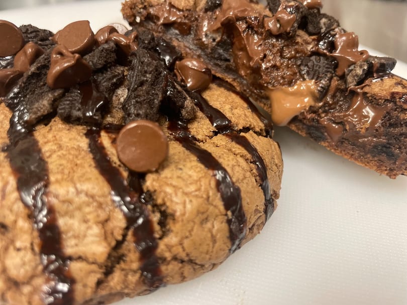 Two chocolate chip cookie desserts, drizzled with chocolate sauce and topped with chocolate chips and cookie crumbles.